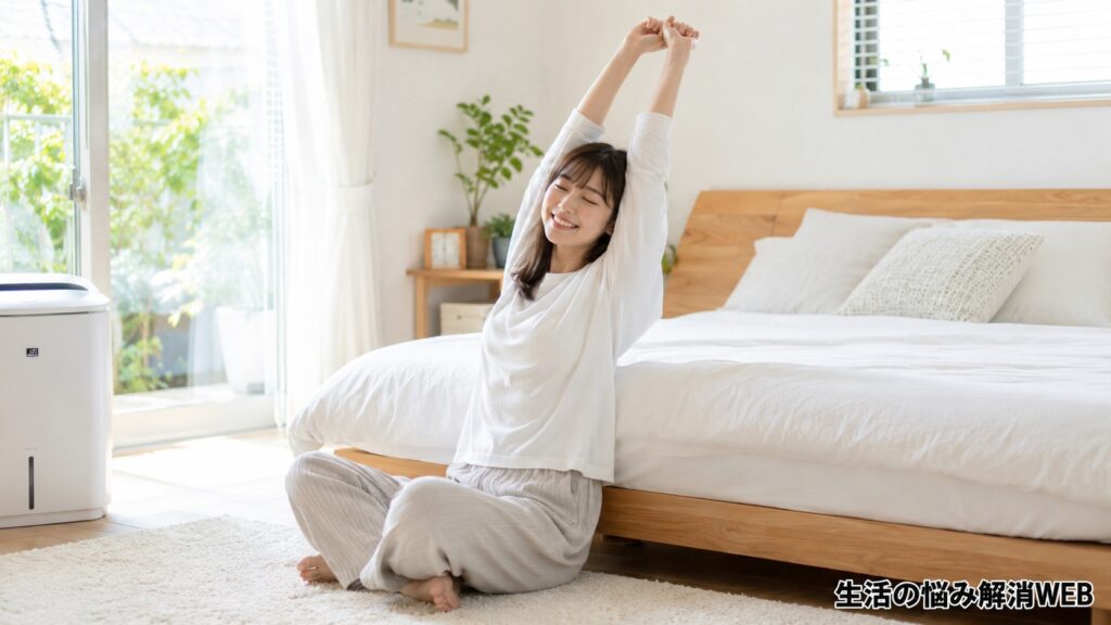 清潔で明るい寝室のベッド横で、マットレスのカビ対策後に気持ちよく伸びをしている若い女性