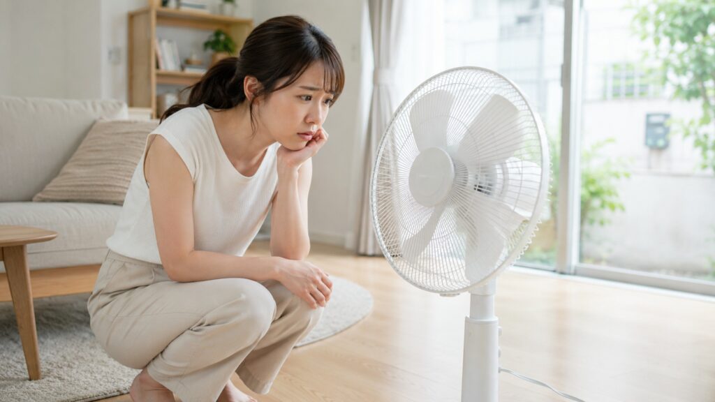 扇風機の異音にどうしたら良いか悩む女性の姿
